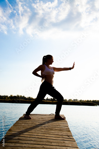 girl doing yoga and sports martial arts on a bridge on a lake