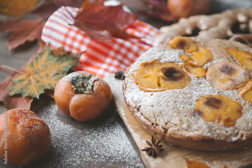 autumn homemade cake with persimmons and powdered sugar, autumn fallen maple leaves, anise,