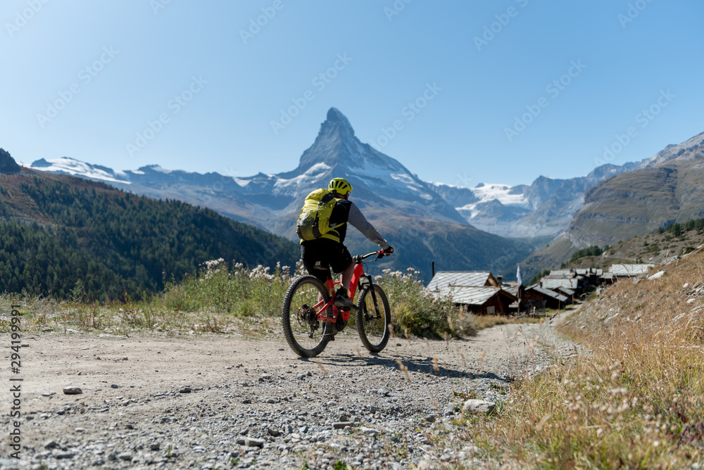 Biker in front of the the mountain Matterhorn, Zermatt, Valais in the Swiss Alps, blue sky, no clouds in early autumn.