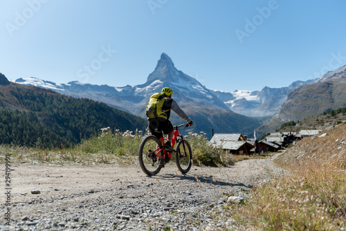 Biker in front of the the mountain Matterhorn, Zermatt, Valais in the Swiss Alps, blue sky, no clouds in early autumn.