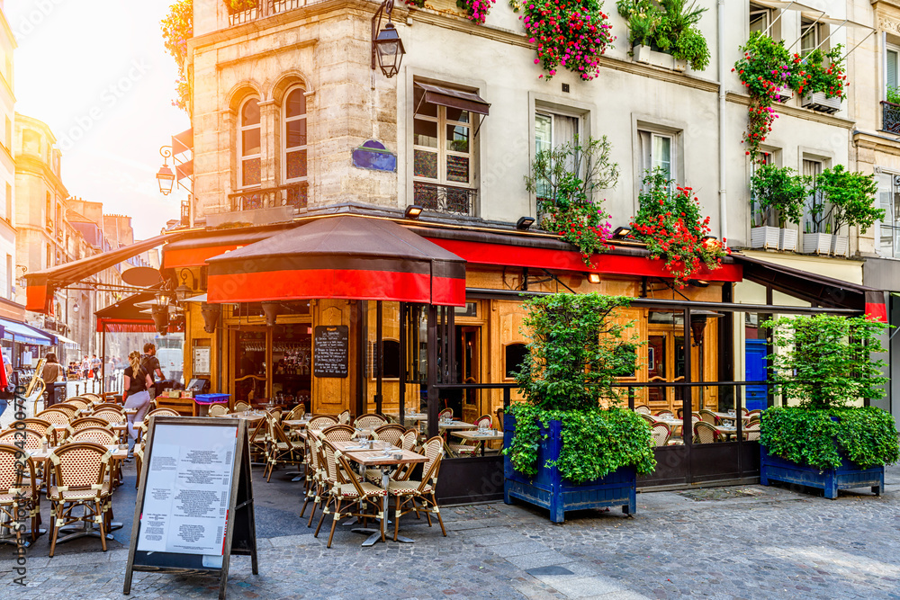 Fototapeta premium Przytulna ulica ze stolikami kawiarni w Paryżu, Francja. Architektura i punkt orientacyjny Paryża. Przytulny gród Paryża.