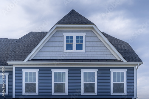 Gable with horizontal vinyl lap siding, double hung window with white frame, shingle facade on a pitched roof attic at an American luxury single family colonial home neighborhood in the USA