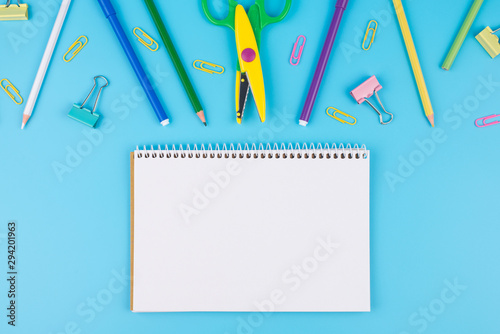 Colorful school supplies and notepadon a blue background. School notebook and various colored stationery. Back to school concept.