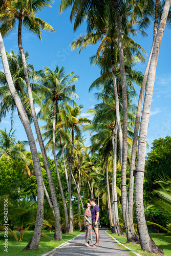 Young couple in love walking on exotic island  by the coconut palms. Happy couple enjoying in walk