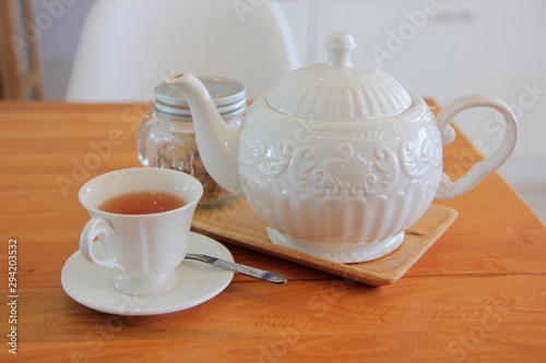 Tea pot in white cup and brown wooden background.