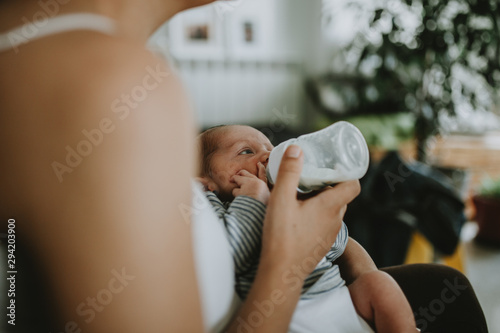 Closeup portrait of 1 month old baby eating milk from bottle photo