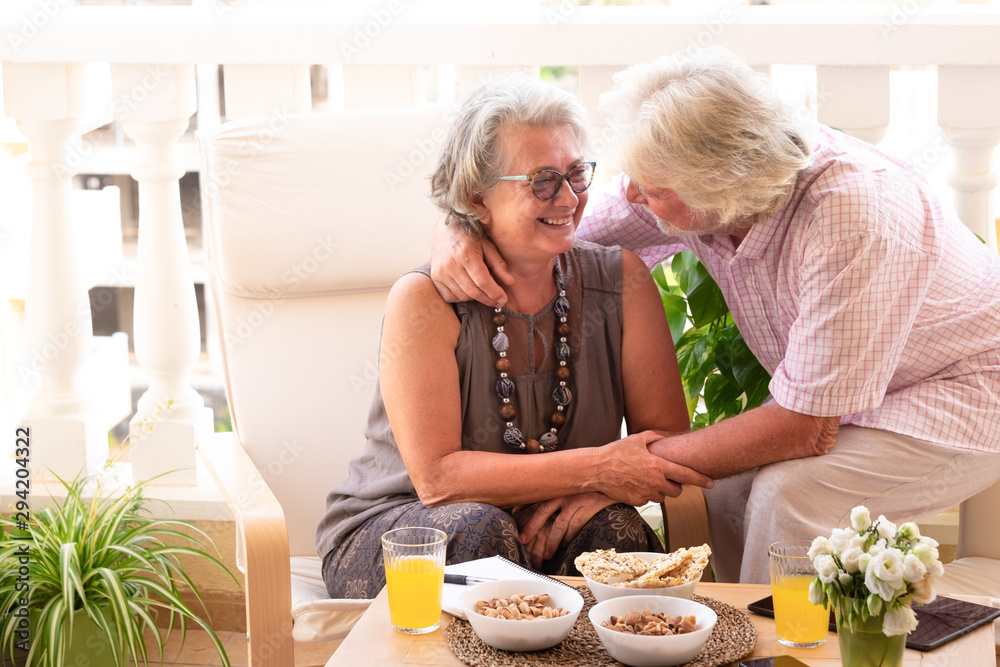 Laugh and happiness for two attractive elderly people relaxing outdoor on terrace. Table with food and drink