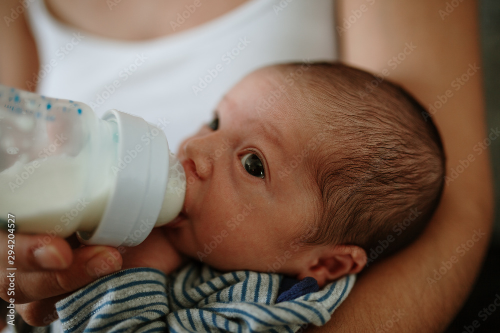 Closeup portrait of 1 month old baby eating milk from bottle Closeup portrait of 1 month old baby eating milk from bottle