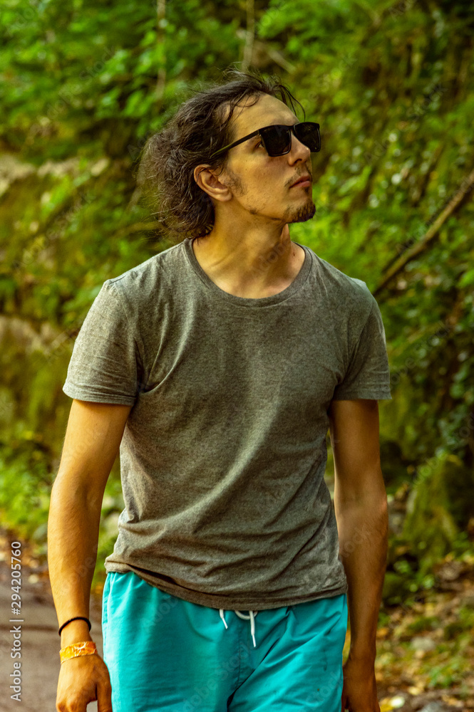 Walk in the fresh air. A young man with glasses looks at the nature around him. A man walks along the road. Walk in the fresh air. A young man with glasses looks at the nature around him. A man walks along the road.