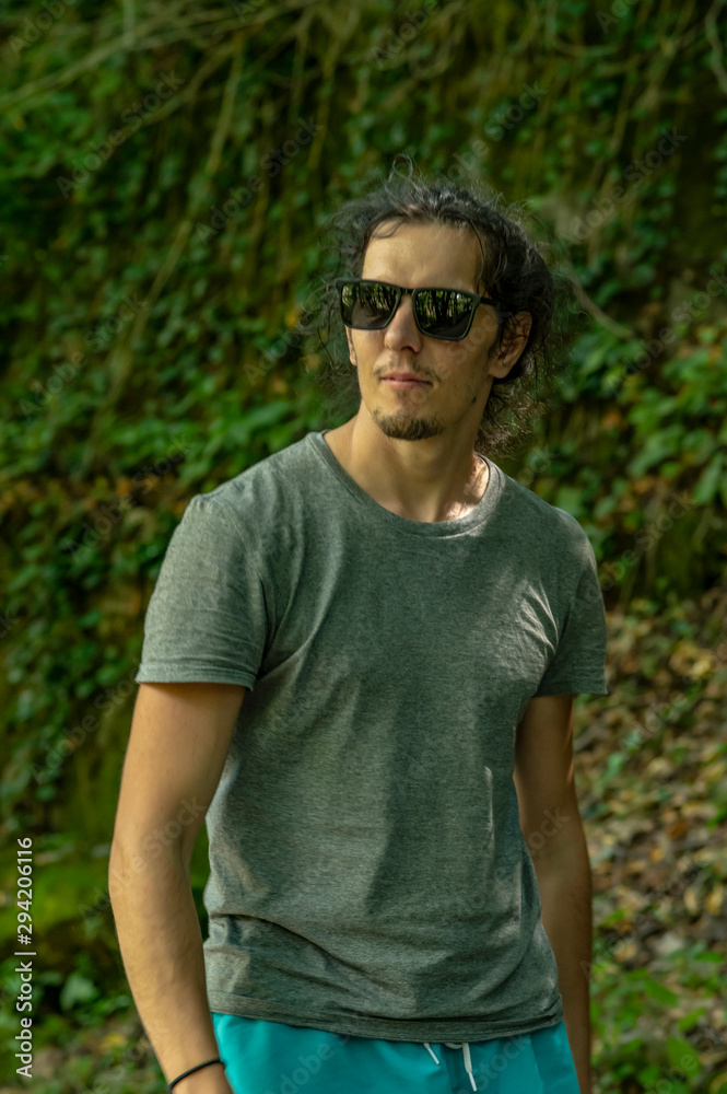 Walk in the fresh air. A young man with glasses looks at the nature around him. A man walks along the road. Walk in the fresh air. A young man with glasses looks at the nature around him. A man walks along the road.