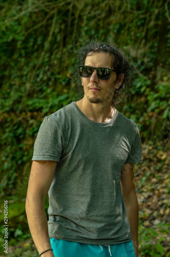 Walk in the fresh air. A young man with glasses looks at the nature around him. A man walks along the road.