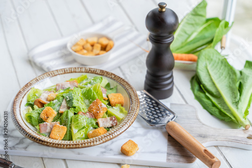 Fresh Green organic Caesar salad on the white wooden table.