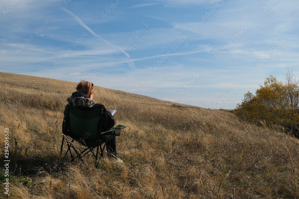 girl reads a book on a chair in the steppe in autumn girl reads a book on a chair in the steppe in autumn