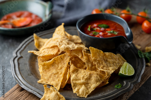 Traditional Mexican appetizers of hot crispy nachos with tomato salsa sauce dip.