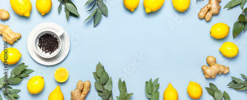 Creative food concept. Fresh ginger root, cup tea with brewing inside, lemon, eucalyptus leaves on blue background. Flat lay top view copy space. Minimalistic style seasoning spice ingredient for tea