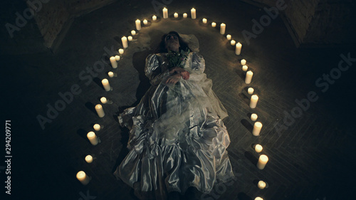 Sorrow scene of a corpse bride on the floor like a ritual with candles photo