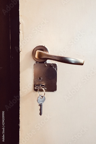 Key inside a key hole on white door with handle