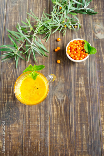 Fresh tea from sea buckthorn berries with mint leaves on a wooden dark table. Healthy drink