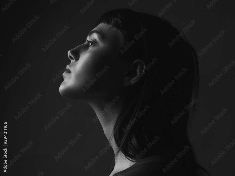 Young woman in profile close up. Black and white. Low key