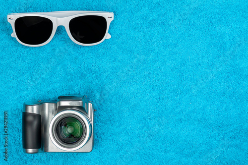 Sunglasses and a camera lie on a towel.