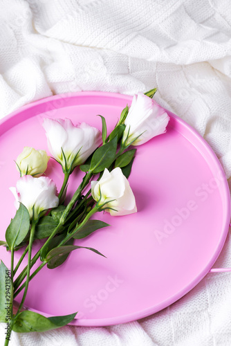 Gift pastel flowers eustoma for Valentines or Mothers day on pink tray on bed . Flat lay style.