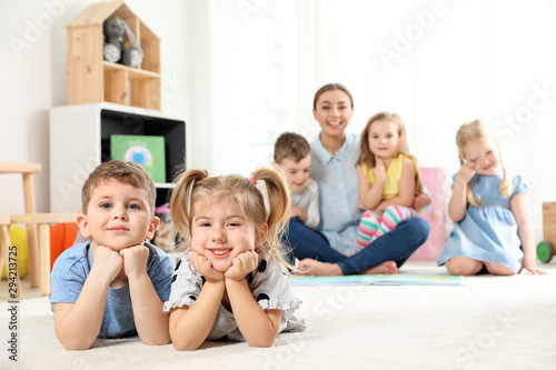 Playful little children lying on floor indoors. Space for text