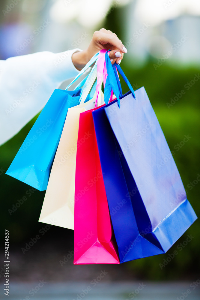 Black friday. Happy woman near shopping mall holding gift bags