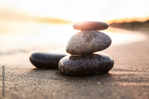 Dark stones on sand near sea at sunset. Zen concept