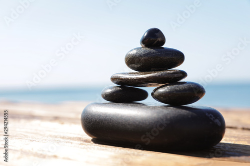 Stack of stones on wooden pier near sea  space for text. Zen concept
