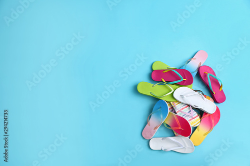 Heap of different flip flops and space for text on blue background, top view. Summer beach accessories