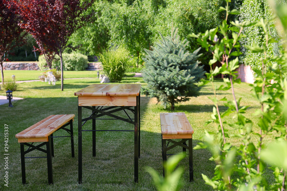 Wooden picnic table with benches in green park Wooden picnic table with benches in green park
