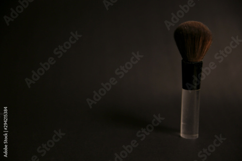 an image of a cosmetic powder brush, thrown in white loose powder, shot on black backgrownd.