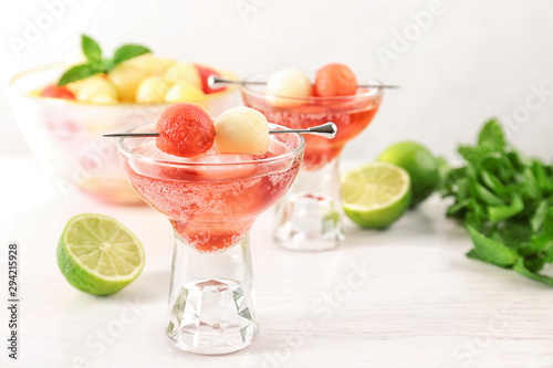 Glass of melon and watermelon ball cocktail on white wooden table