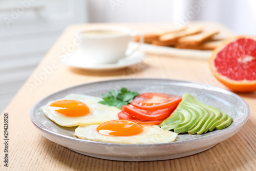 Plate with fried eggs and vegetables on wooden table. Healthy breakfast