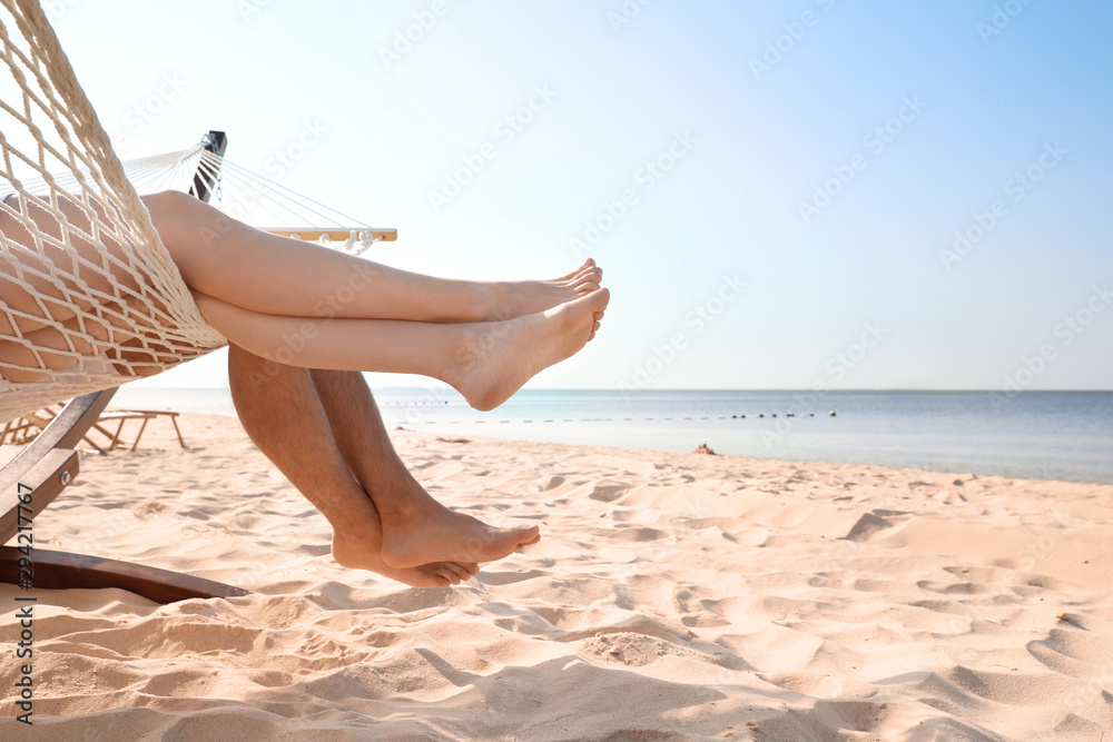Young couple relaxing in hammock on beach, closeup - obrazy, fototapety, plakaty 