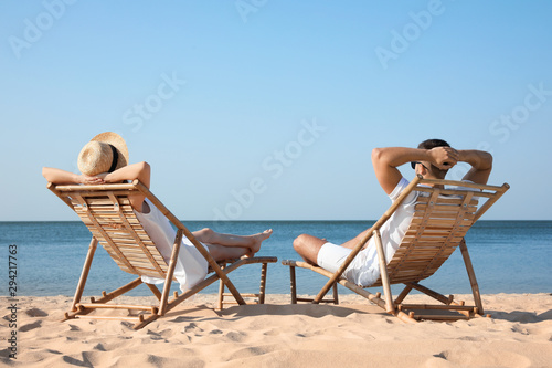 Young couple relaxing in deck chairs on beach Tapéta, Fotótapéta
