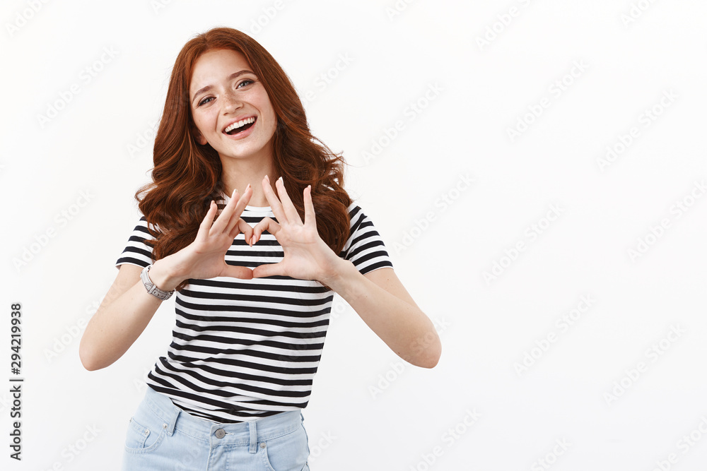 Love, friendship and wellbeing concept. Cute redhead silly girl in striped t-shirt showing heart sign and smiling happily, cherish relationship, confess sympathy, stand enthusiastic white background Love, friendship and wellbeing concept. Cute redhead silly girl in striped t-shirt showing heart sign and smiling happily, cherish relationship, confess sympathy, stand enthusiastic white background