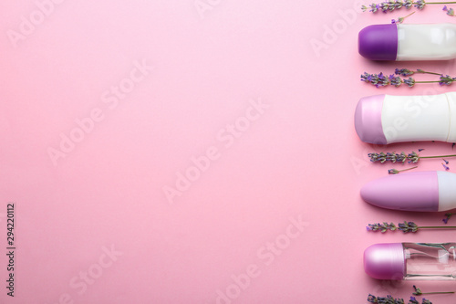 Different female deodorants and lavender flowers on pink background, flat lay. Space for text