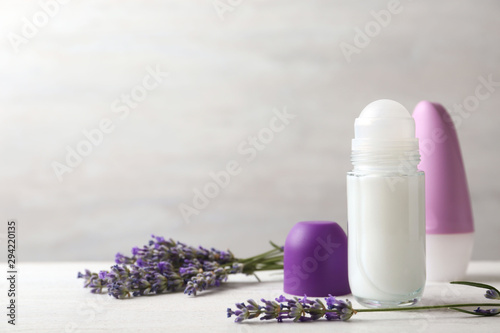 Female deodorants and lavender flowers on white wooden table. Space for text