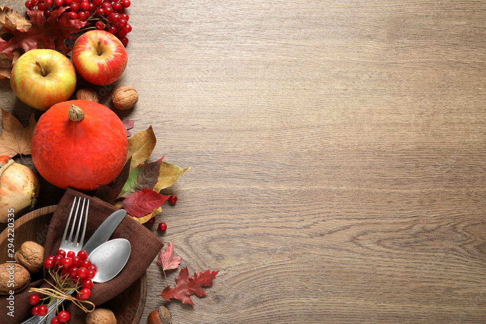 Autumn vegetables, fruits and cutlery on wooden background, flat lay with space for text. Happy Thanksgiving day