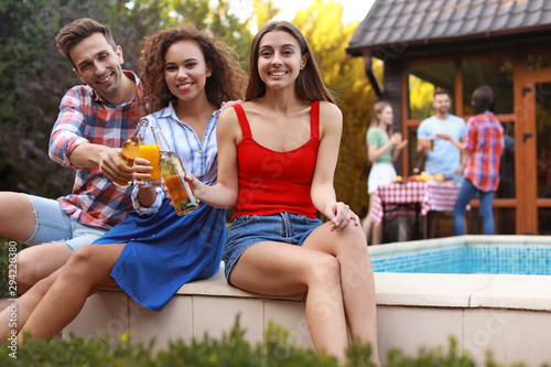 Happy friends with drinks at barbecue party near swimming pool outdoors © New Africa
