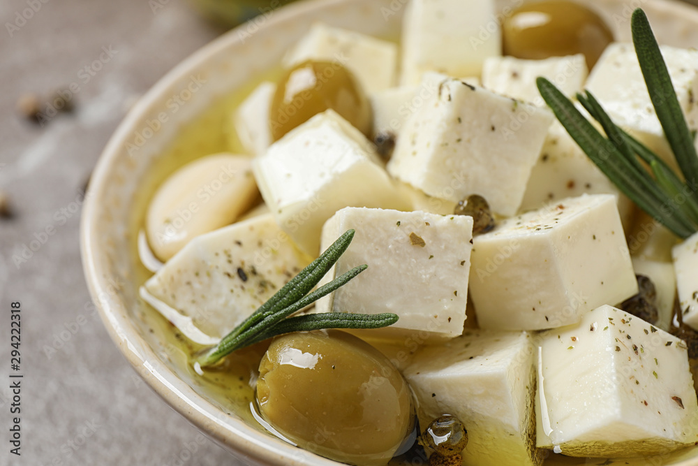 Pickled feta cheese in bowl on light brown table, closeup