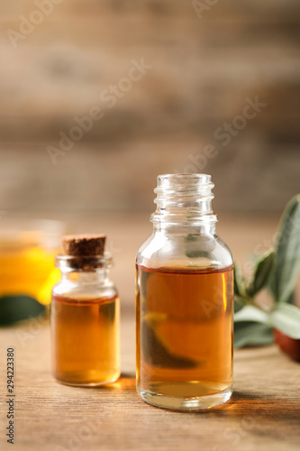 Glass bottles with jojoba oil on wooden table