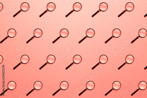 Trendy pattern made with Magnifying glass on bright light coral background. Concept information search. Minimal style with colorful paper backdrop. Minimal creative concept. Living coral