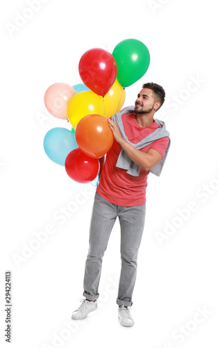 Young man holding bunch of colorful balloons on white background