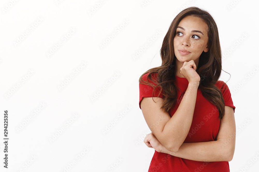 Hmm sounds interesting. Intrigued smart cute brunette woman in red t-shirt pondering, deep focus on thought, making plan, look left with thoughtful expression, touch chin, standing white background Hmm sounds interesting. Intrigued smart cute brunette woman in red t-shirt pondering, deep focus on thought, making plan, look left with thoughtful expression, touch chin, standing white background