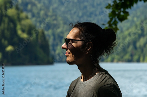 A man with sunglasses in the background of a lake