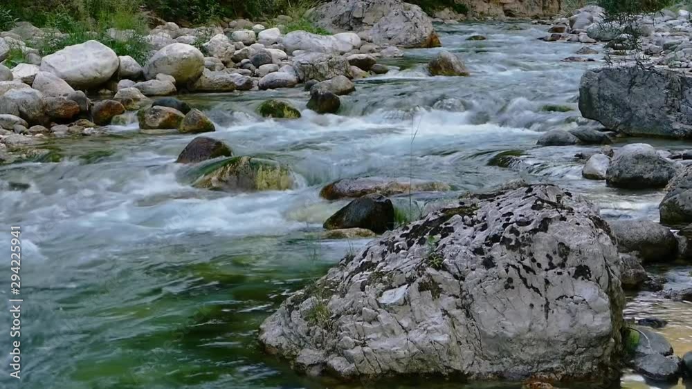 Close up of fast moving stream between rocks and boulders in North Italy. Static handheld shot Close up of fast moving stream between rocks and boulders in North Italy. Static handheld shot