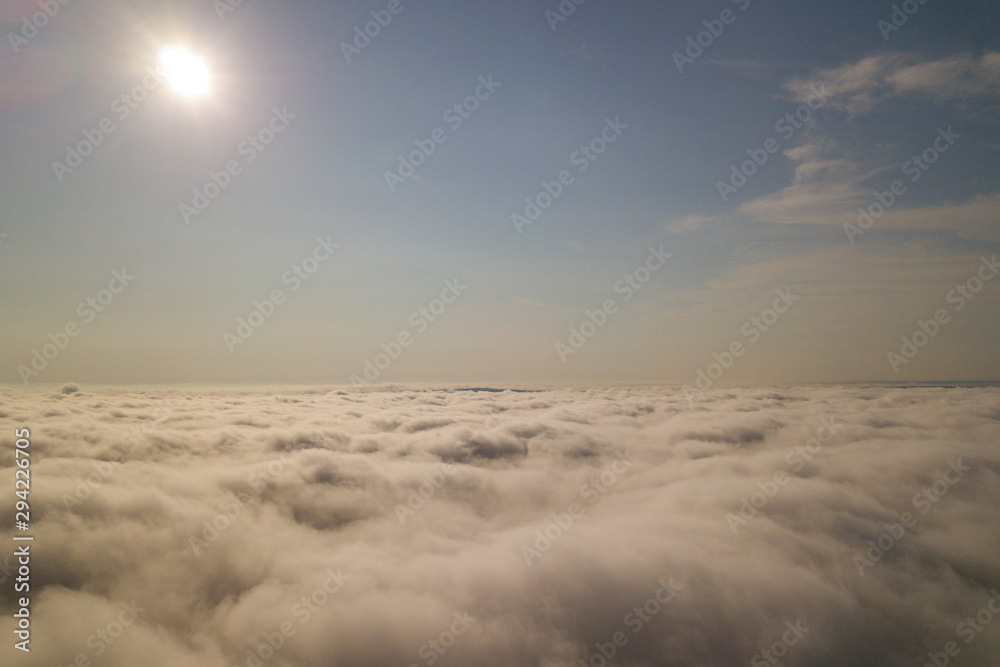 Aerial view over white clouds and clear blue sky.