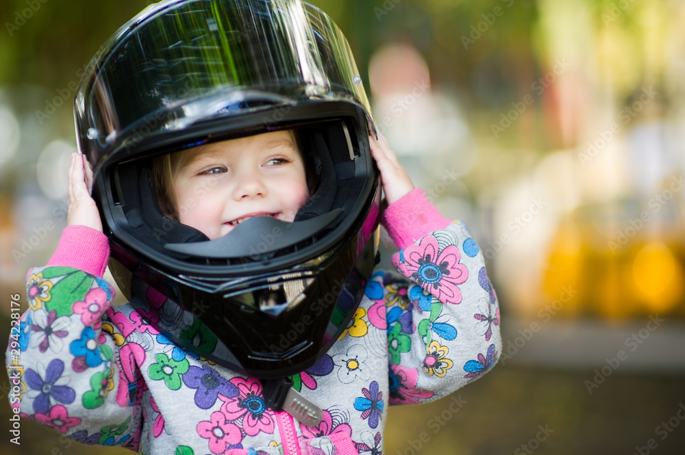 portrait of a cute girl in a big motorcycle helmet on a background of very blurry autumn foliage. close up portrait of a cute girl in a big motorcycle helmet on a background of very blurry autumn foliage. close up
